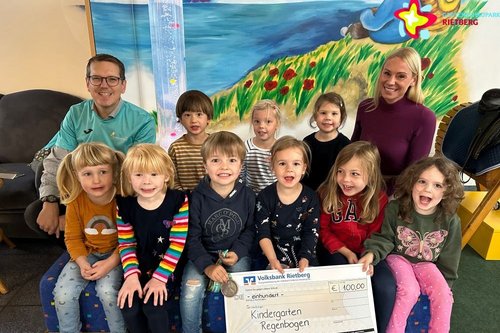 Sponsorin, Organisator und Kinder aus dem Kindergarten Regenbogen mit Scheck.