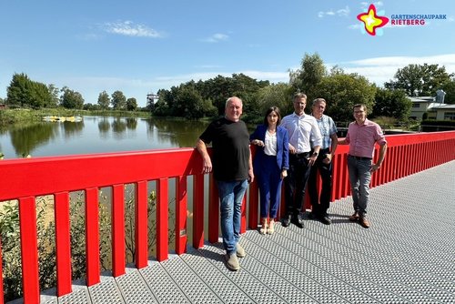 Parkmeister Helmut Kammermann, Nina Seppeler, Michael Pauleickhoff, Alexander Warkentin und Park-Geschäftsführer Johannes Wiethoff stehen auf der nun wieder feuerroten Sepper-Brücke, im Hintergrund der Obersee samt Aussichtsturm.