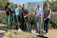 FöJ'ler Fynn Wittreck mit seinen Kollegen vor dem Gartenschaupark-Rietberg-Schild. Alle haben Schaufeln, Besen und Rechen in den Händen.