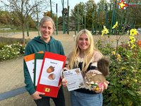 Andrea Sassenberg mit Tafel der Herbstrallye und Bianca Piekatz mit Rätselkarten, einem Deko-Eichhörnchen und kleinen Preisen.